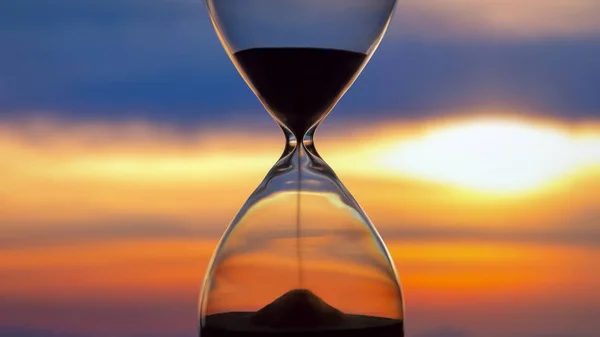 Hourglass on the background of a sunset. The value of time in li — Stock Photo, Image