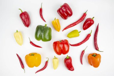 Beyaz arka planda farklı renkte tatlı ve acı biberler.
