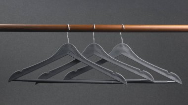 Boş gri plastik elbise askısı koyu bir arka planda asılı.. 