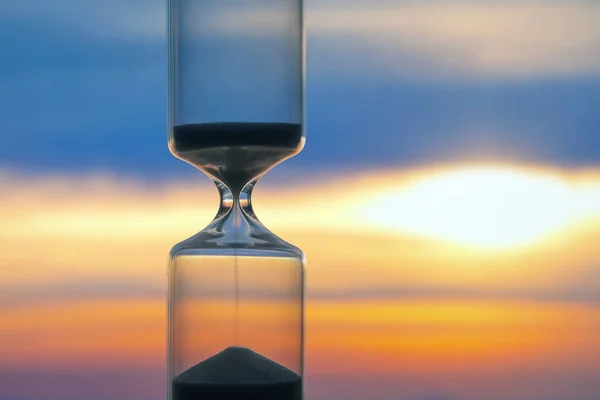 Hourglass on the background of a sunset. The value of time in li — Stock Photo, Image