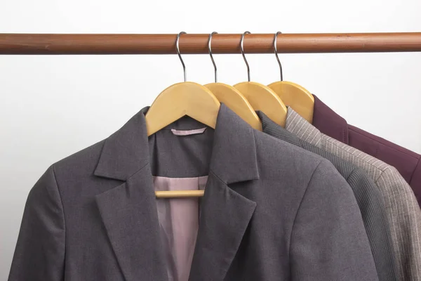Different women's office classic jackets hang on a hanger for st