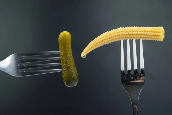 Pickled cucumber and corn on a fork close-up on a dark backgroun — Stock Photo, Image