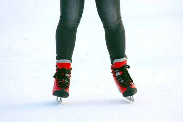 Pernas femininas em patins em uma pista de gelo. Desporto e entretenimento. R — Fotografia de Stock