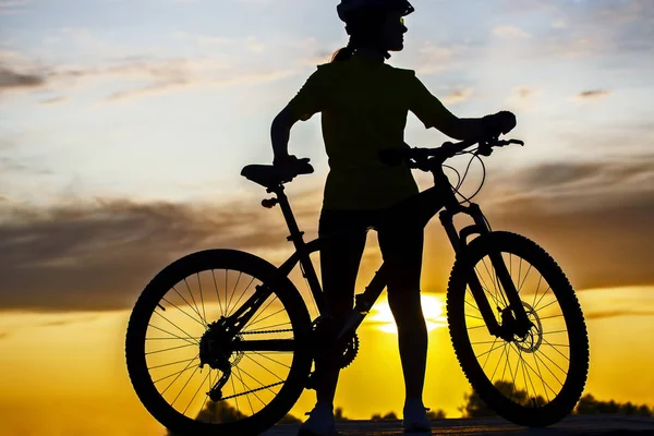 Silhouette eines Radfahrermädchens mit einem Fahrrad auf dem Hintergrund von — Stockfoto