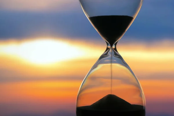 Hourglass on the background of a sunset. The value of time in li — Stock Photo, Image