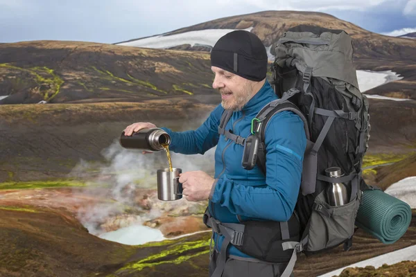 Счастливый турист наливает горячий чай из термоса на фоне о — стоковое фото