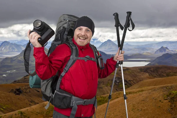 Улыбающийся турист в красной куртке с фотоаппаратом в руках — стоковое фото