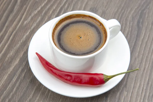 Black coffee in a white cup with red hot pepper on a plate. Spic Royalty Free Stock Photos