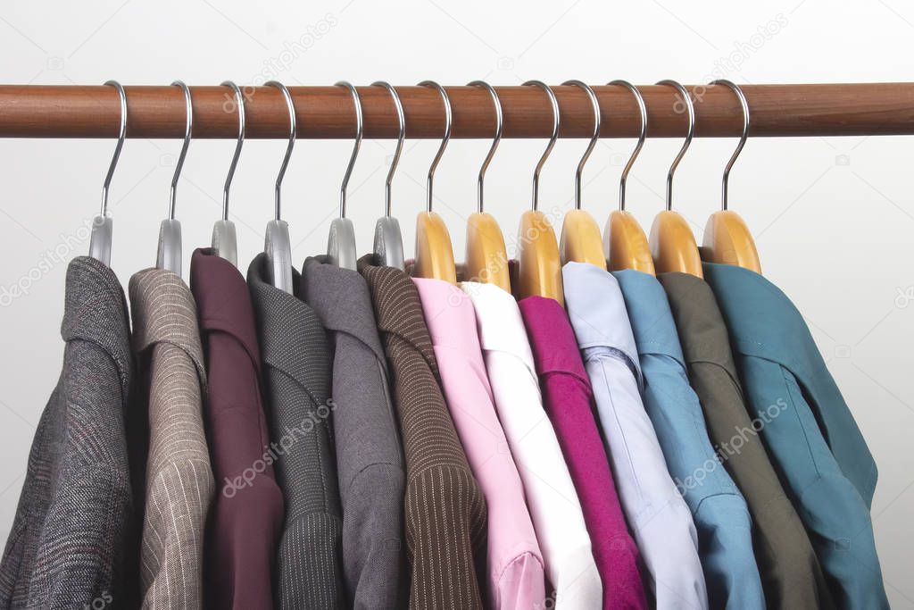 Different women's office classic jackets and shirts hang on a ha