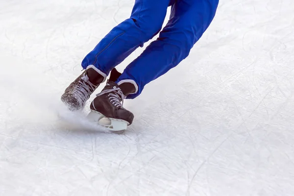穿着冰鞋的人的腿在冰球场上积极滑冰 — 图库照片