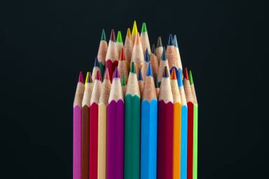 Koyu bir arkaplana çizim yapmak için renkli kalemler. Eğitim ve 