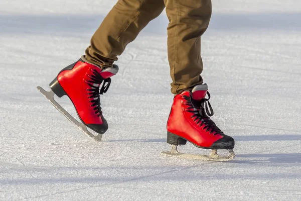 Las piernas femeninas patinan activamente en patines rojos en una pista de hielo. H — Foto de Stock