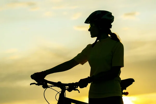 Silhouette eines Radfahrermädchens mit einem Fahrrad auf dem Hintergrund von — Stockfoto