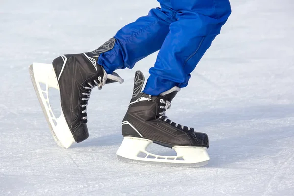 Gambe di un uomo pattina attivamente su una pista di pattinaggio su ghiaccio. Interessi e sport — Foto Stock