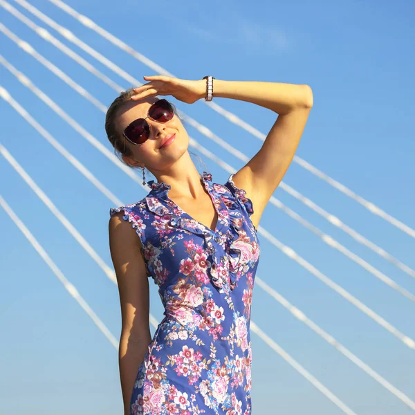 Jovem menina bonita em óculos de sol olhando para o sol no blu — Fotografia de Stock