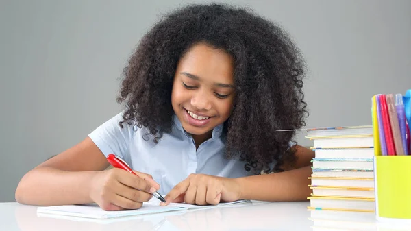 Menina da escola preta escreve em um caderno, fazendo homewor — Fotografia de Stock