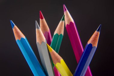 Koyu bir arkaplana çizim yapmak için renkli kalemler. Eğitim ve 