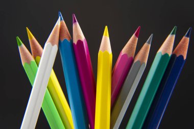 Koyu bir arkaplana çizim yapmak için renkli kalemler. Eğitim ve 