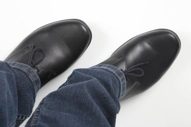 Beyaz arka planda kot pantolon ve siyah klasik ayakkabı erkek bacakları