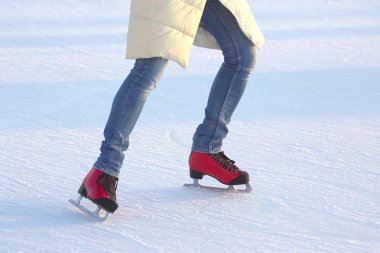 Mavi kotlu kız aktif olarak buz üstünde kırmızı buz pateni yapıyor.