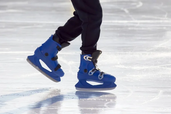 Patas de un hombre en patines azules monta en una pista de hielo. pasatiempos y l — Foto de Stock