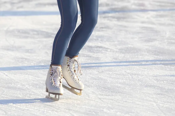 Gambe di una ragazza in jeans blu e pattini bianchi su una pista di pattinaggio su ghiaccio. ho — Foto Stock