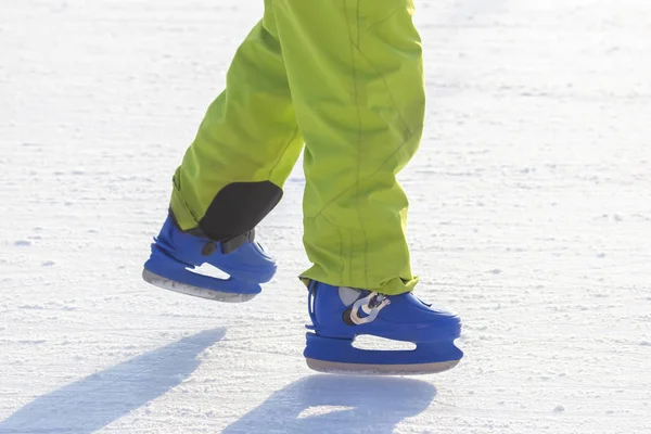 Pernas de um homem de patins azuis passeios em uma pista de gelo. hobbies e l — Fotografia de Stock
