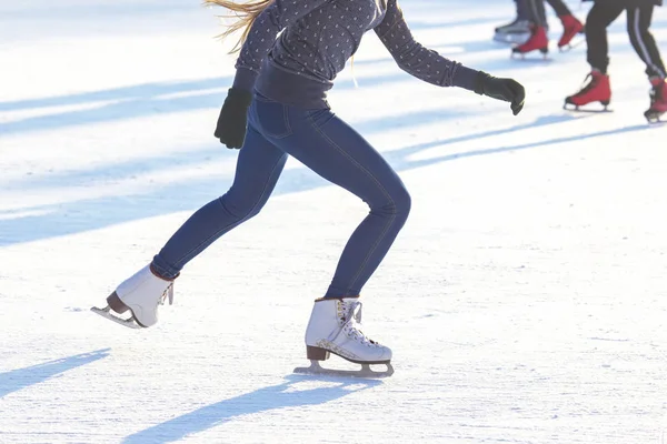 La muchacha en los vaqueros azules patina activamente sobre los patines blancos sobre el rin de hielo —  Fotos de Stock