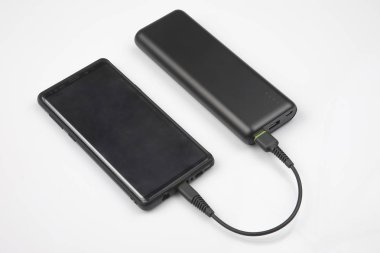 Power Bank beyaz arka planda akıllı telefon bataryası şarj ediyor. di