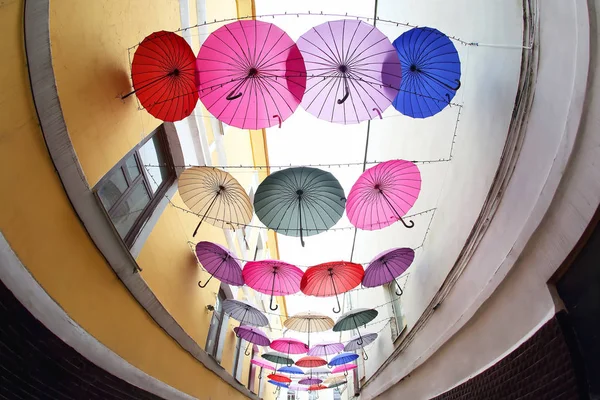 Coloridos paraguas decorativos cuelgan entre los edificios como prot — Foto de Stock