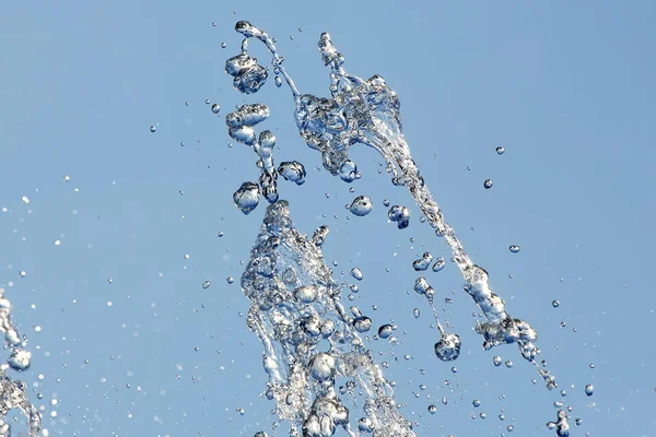 Spatten van vliegende water uit de fontein tegen de blauwe hemel — Stockfoto