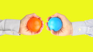 Men's hands with colorful plastic balls on yellow background