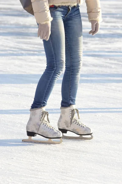 Legs of a girl in blue jeans and white skates on an ice rink. ho — Stok fotoğraf