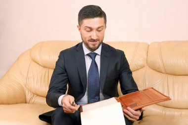 successful business man with business documents sitting on a lea