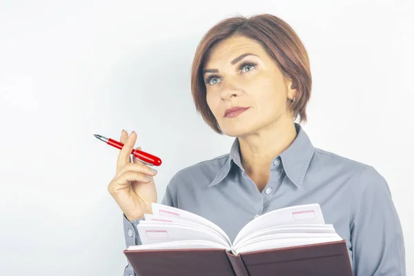 Chica de negocios con un bolígrafo rojo y cuaderno en las manos en una ba blanca — Foto de Stock