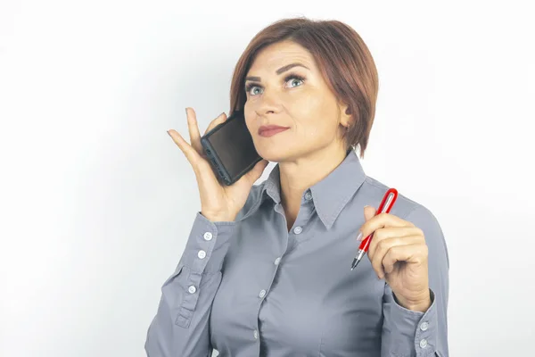Business beautiful woman speaks on the phone with a pen in her h — Stockfoto