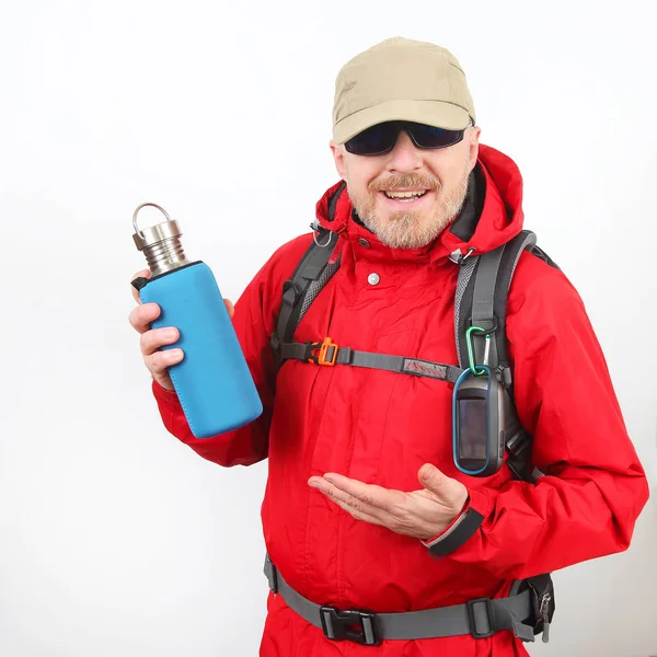 Tourist traveler in a red jacket shows a metal bottle for water — Stockfoto