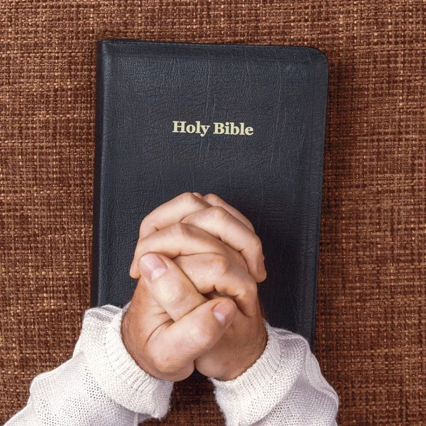 Las manos dobladas del hombre en la santa biblia — Foto de Stock