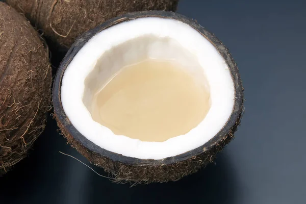 cut fresh coconut with real coconut milk on a dark background. vitamin fruits. healthy food