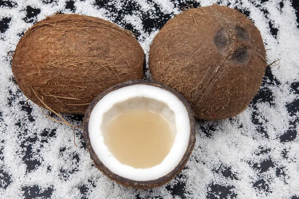 cut fresh coconut with real coconut milk on a dark background of coconut flakes. vitamin fruits. healthy food