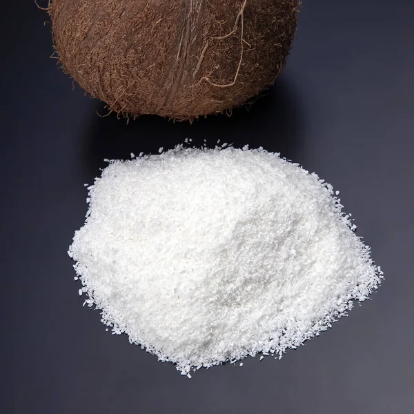 Coconut flakes on a dark background next to a coconut. vitamin fruits. healthy foo