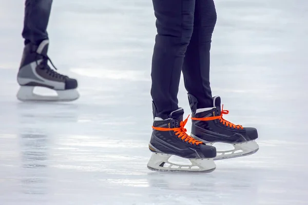 Legs of a man skating on an ice rink. Hobbies and sports. Vacations and winter activities.