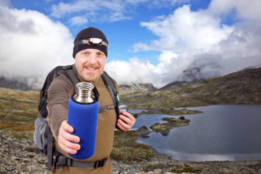 Dağ gölü manzaralı. Jotunheimen Ulusal Parkı. Norveç. Turist su için metal bir şişe gösteriyor.