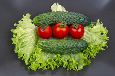 Taze salatalık, domates ve gri tabakta marul. Vitaminler ve hafif kahveler