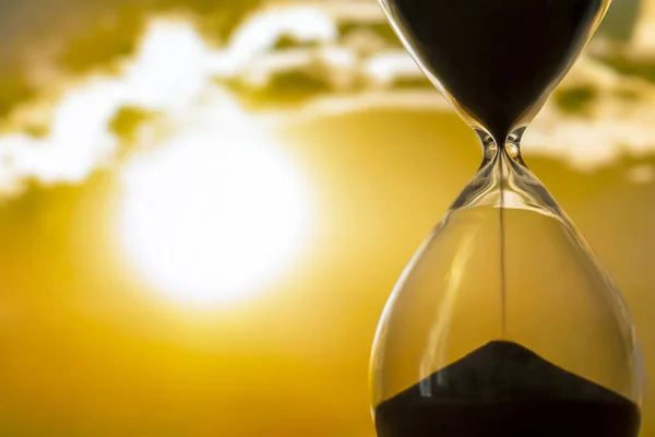 Hourglass on the background of a sunset. The value of time in life. time measuring tool. An eternity.