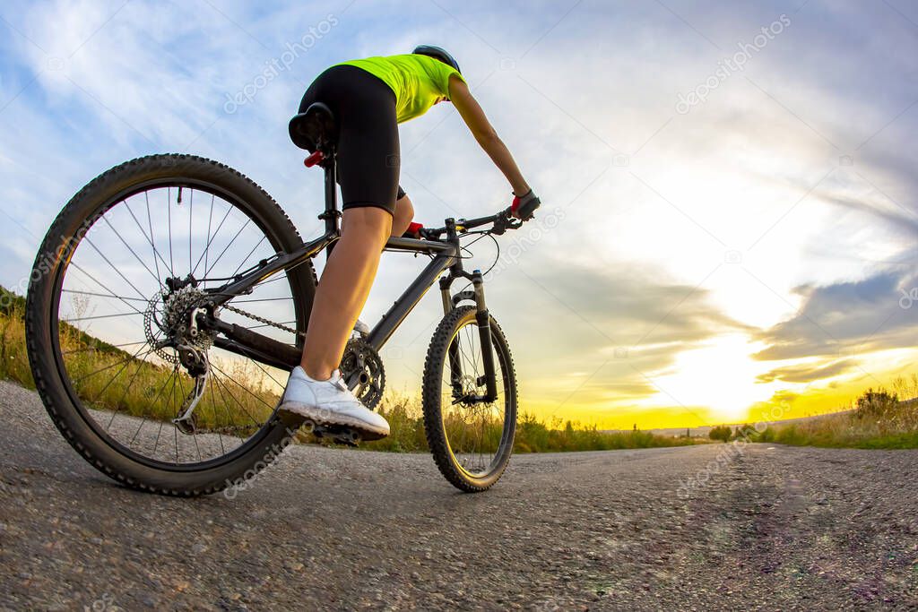 Beautiful sporty cyclist rides a bicycle on the road against the backdrop of beautiful nature and sunset. hobbies and sport
