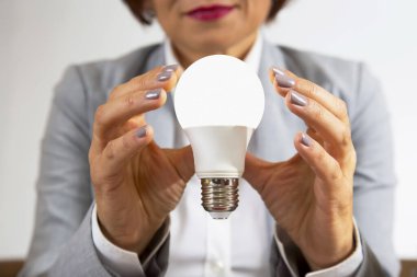 Takım elbiseli bir iş kadını elinde yakın plan bir elektrik lambası tutuyor.
