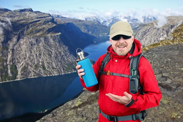 Турист Красной Куртке Показывает Металлическую Бутылку Воды Озеро Языке Троллей — стоковое фото