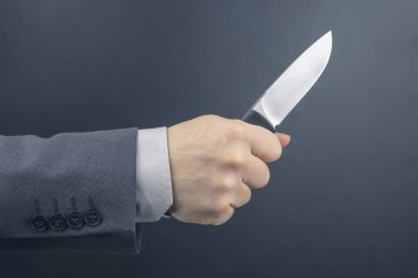 Bir iş adamının erkek eli bıçak tutuyor. Tehdit ve suç faaliyetleri. temel yaşam aracı