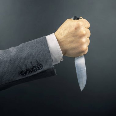 Bir iş adamının erkek eli bıçak tutuyor. Tehdit ve suç faaliyetleri. temel yaşam aracı